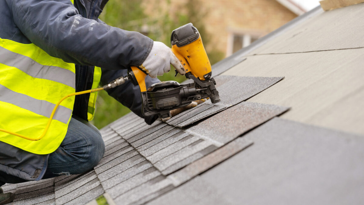 Roofer installing shingles on home